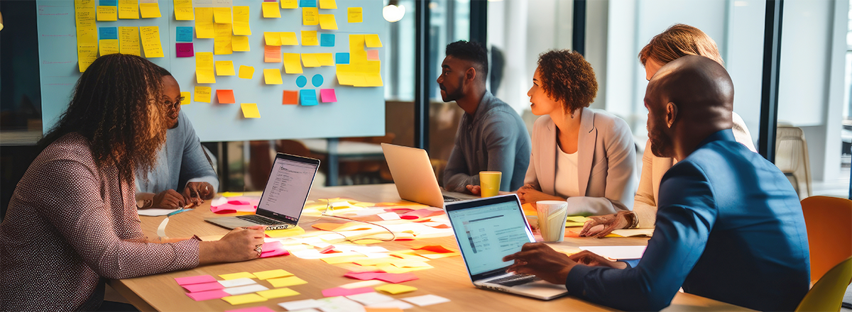A team of professionals around a conference table strategizing with sticky notes and a whiteboard.