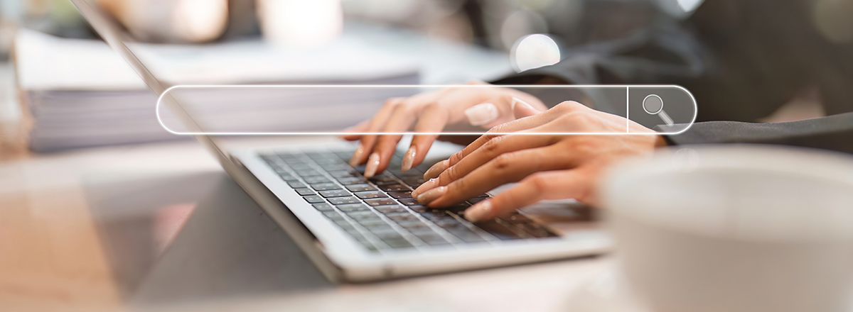 A woman's hands typing on a laptop with a search bar superimposed on the image.