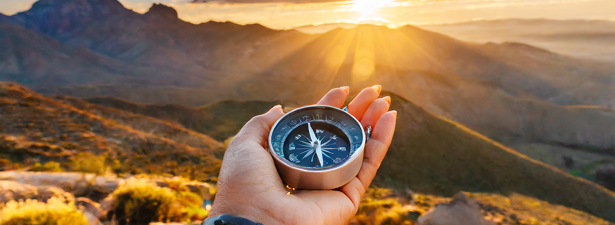 Woman holding a compass on a mountain.