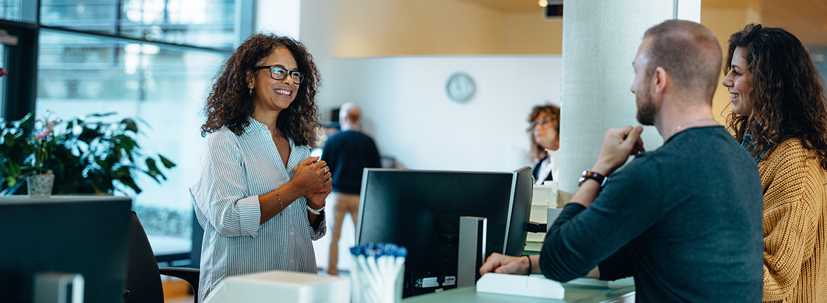 Woman talks to couple inside government building.